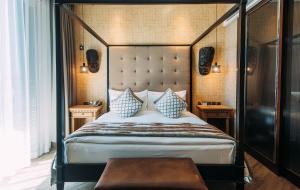 Orient-Anyi international Hotel في بكين: غرفة نوم بسرير مظلة مع طاولتين