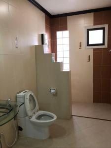 a bathroom with a toilet and a sink and a window at Siwasom Resort Sakon Nakhon in Sakon Nakhon