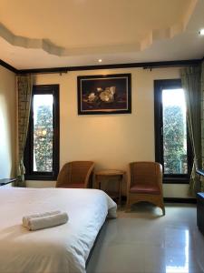 1 dormitorio con 1 cama, 2 sillas y ventanas en Siwasom Resort Sakon Nakhon, en Sakon Nakhon