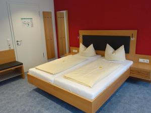 ein großes Bett in einem Schlafzimmer mit einer roten Wand in der Unterkunft Hotel Gasthaus Krone in Immenstaad am Bodensee