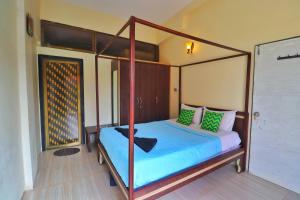 um quarto com uma cama de dossel com lençóis azuis e almofadas verdes em Casa Greenwood Pure Veg Villa With Common Pool em Lonavala