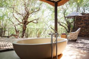 a bath tub sitting in front of a large window at Molori Safari in Derdepoort
