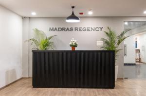 a reception desk in a lobby with a marias recovery sign at Madras Regency in Chennai