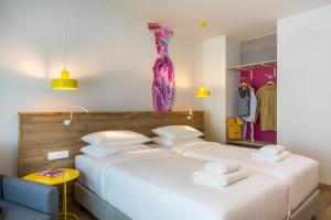 a bedroom with two beds and a dress on the wall at ibis Styles Athens Routes in Athens