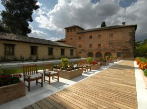 una terraza de madera con sillas y un edificio en Parador de Granada, en Granada