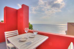 a white table with two wine glasses on a balcony at Studio in the Red Wall building by Ricardo Bofill - MURALLA ROJA in Calpe