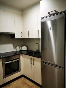 a kitchen with a stainless steel refrigerator and white cabinets at A Casa de Matelos in A Lanzada