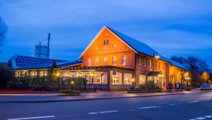 a large brown building with lights on it at night at Gasthaus Kempermann in Großenkneten