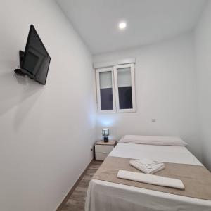 a room with two beds and a tv on the wall at Hostal Las Fronteras in Torrejón de Ardoz