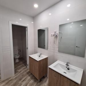 a bathroom with a sink and a mirror and a toilet at Hostal Las Fronteras in Torrejón de Ardoz