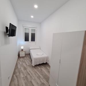 a white room with a bed and a television at Hostal Las Fronteras in Torrejón de Ardoz +24 photos