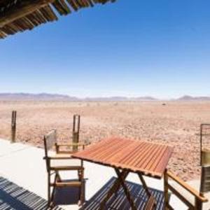 a table and chairs on the beach with a view of the desert at Elegant Desert Camp in Sesriem