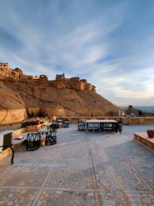 a patio with tables and chairs in front of a mountain at Moustache Jaisalmer in Jaisalmer