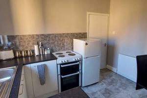eine Küche mit einem weißen Herd und einem Kühlschrank in der Unterkunft Zara Apartments in Dundee