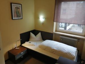 Hotel Augsburg Goldener Falke في اوغسبورغ: غرفة نوم صغيرة بها سرير ونافذة