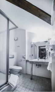 a white bathroom with a sink and a toilet at Hotel Zur Post in Wiehl