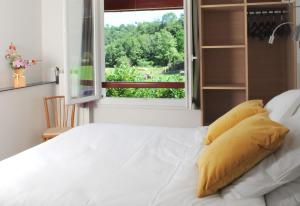 Cette chambre dispose d'un lit avec des oreillers jaunes et d'une fenêtre. dans l'établissement Logis Hotel Xoko-Goxoa, à Saint-Michel