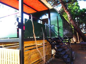 a train sitting under a tree next to a building at La Gare De Millas Chambres d'h&ocirc;tes in Millas