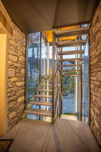a wooden staircase in a room with a stone wall at L'Atelier du Temps - Les Greniers Appartements in Aosta