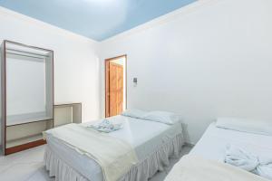 Duas camas num quarto branco com uma janela em Pousada Santa Fé em Aracaju