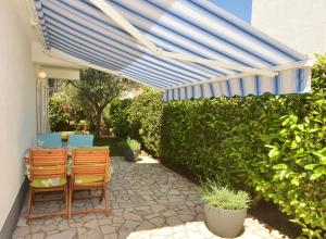 a patio with two chairs and a blue umbrella at Apartment Gerber Krk in Krk