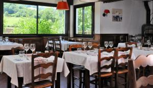 un restaurant avec des tables blanches, des chaises et des fenêtres dans l'établissement Logis Hotel Xoko-Goxoa, à Saint-Michel