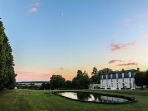 a house and a pond in a field with a building at Domaine de Montchevreuil in Fresneaux-Montchevreuil