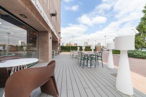 eine Terrasse mit Tischen und Stühlen an einem Gebäude in der Unterkunft Ibis Alcala de Henares La Garena in Alcalá de Henares
