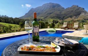 a table with a plate of food and a bottle of wine at Alluvia Boutique Winery & Luxury Accommodation in Stellenbosch