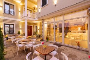 a restaurant with tables and white chairs and windows at Villa Ester in Korçë