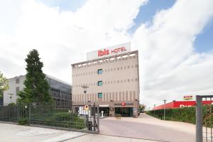 - un grand bâtiment blanc avec un panneau de bus dans l'établissement Ibis Alcala de Henares La Garena, à Alcalá de Henares