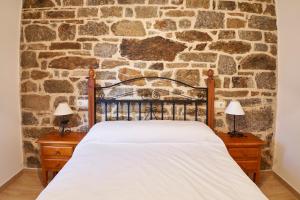 Cama en habitación con pared de piedra en El Mirador de Sanabria en Galende