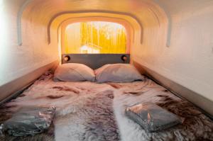 ein kleines Bett in einem Zimmer mit Fenster in der Unterkunft Minicamping Aan de Waterspiegel in Aagtekerke