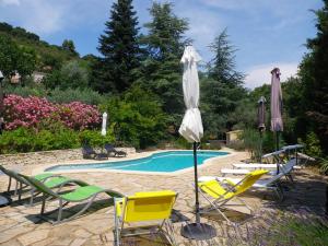 a pool with chairs and umbrellas next to a pool at Mas Du Cadranier in Villeneuve