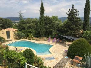 a swimming pool in a yard with chairs and trees at Mas Du Cadranier in Villeneuve