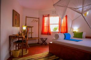 een slaapkamer met een bed, een bureau en een raam bij Dan Stam Hotel in Arusha