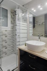 y baño con lavabo blanco grande y ducha. en Acropolis Deluxe Apartment, en Atenas