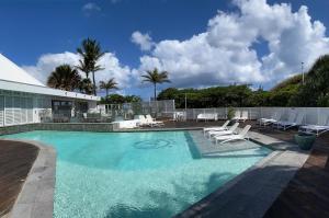 a large swimming pool with white chairs and a house at Villa Delisle Hôtel & Spa in Saint-Pierre