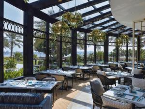 a restaurant with tables and chairs and large windows at Mövenpick Hotel Bahrain in Manama