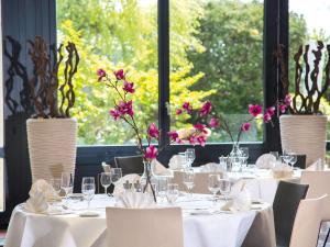 ein Esszimmer mit Tischen und Stühlen mit Blumen in Vasen in der Unterkunft Mövenpick Hotel Egerkingen in Egerkingen