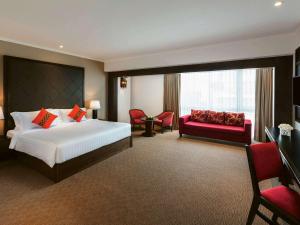 チェンマイにあるスリウォン ホテル チェンマイのベッドと赤いソファが備わるホテルルームです。