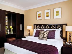 a bedroom with a large bed with purple pillows at Mövenpick Resort Petra in Wadi Musa
