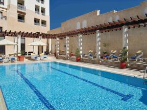 a large swimming pool with chairs and a building at Mövenpick Resort Petra in Wadi Musa