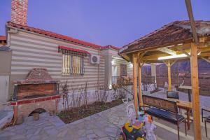 a patio with a fireplace and a wooden gazebo at Vila 1 in Korçë