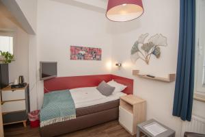 Habitación pequeña con cama roja y TV. en Haus Neunaber en Norderney