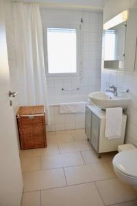 a white bathroom with a sink and a toilet at Modern, bright and spacious 3 bedrooms 2 bathrooms in Lausanne