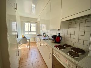 a kitchen with white cabinets and a stove top oven at Near the lake and city center ! in Lausanne