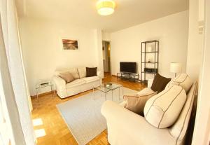 a living room with two white couches and a television at Near the lake and city center ! in Lausanne
