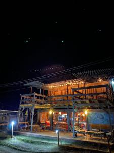 um edifício com mesas e bancos à noite em Mar de Fondo Hostel em Punta Del Diablo
