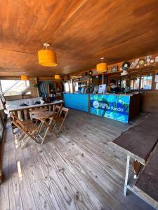 a restaurant with wooden floors and a counter with tables at Mar de Fondo Hostel in Punta Del Diablo